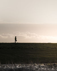 Man running on agricultural field against sky