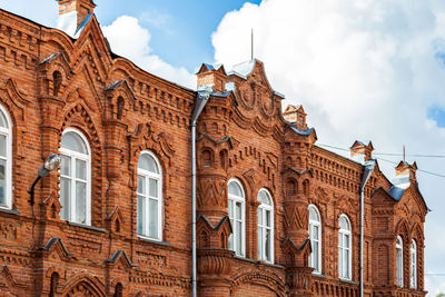 Close-up of a old house a mansion made of old brick with white window against blue sky on summer day