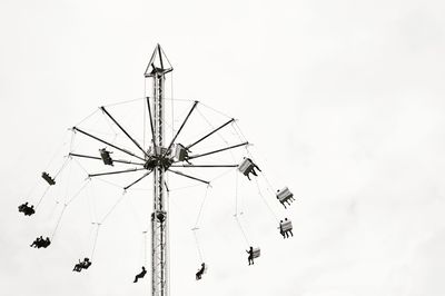 Low angle view of silhouette people on chain swing ride against clear sky