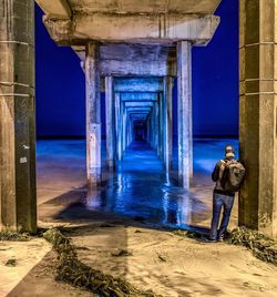 Underneath view of pier with man on beach