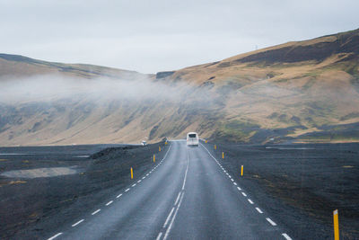 Road leading towards mountain against sky