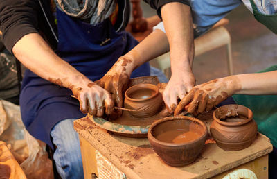 Midsection of people making pottery in workshop