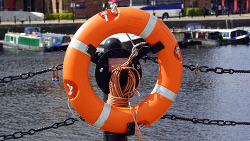 Close-up of orange chain hanging on rope at harbor