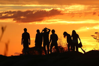 Silhouette people standing against orange sky