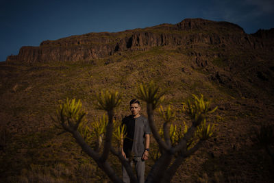 Portrait of young woman standing on mountain against sky