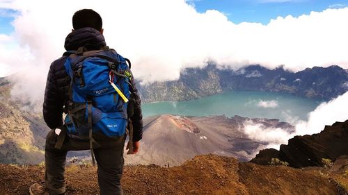 Rear view of people standing on mountain against sky