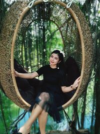 Portrait of young woman standing against trees