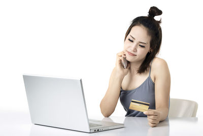 Young woman using mobile phone against white background