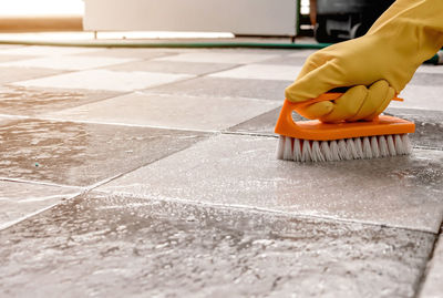 Using a plastic floor scrubber to scrub the tile floor with a floor cleaner.