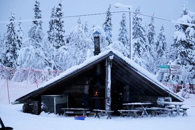 Snow covered houses by trees against mountain