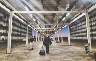 Rear view of people walking in corridor of building