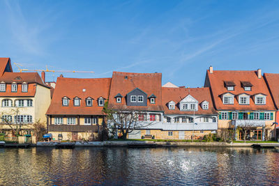 Houses by river against buildings in city