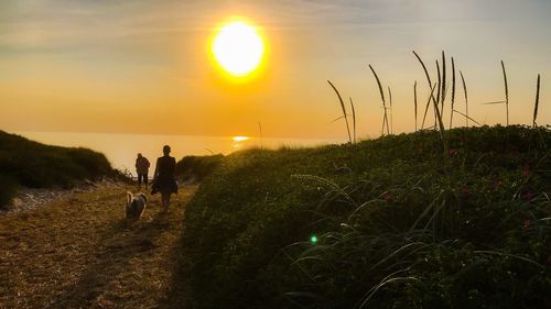 People on field against sky during sunset