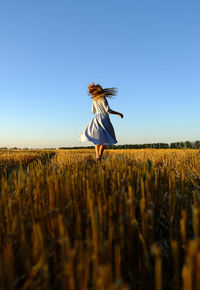 Woman standing on field against clear sky