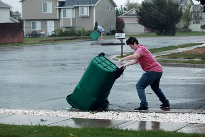 Woman flipping garbage can on street