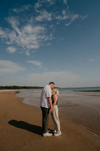 Rear view of woman standing on beach against sky