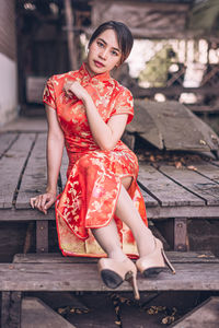 Full length portrait of woman sitting outdoors