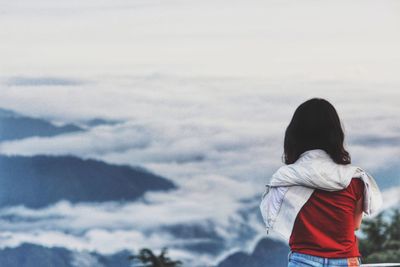 Rear view of woman at clouds covered mountains during winter