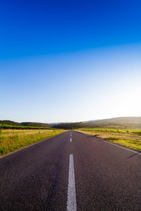 Road passing through landscape against clear sky