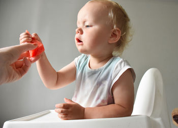 Mom gives a piece of watermelon to her almost 2 years old baby girl.