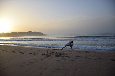 Woman on beach against sky during sunset