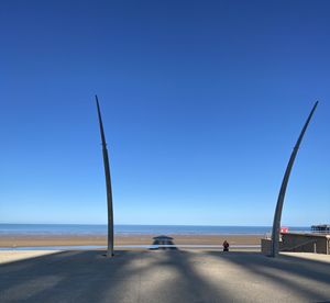 Road by sea against clear blue sky