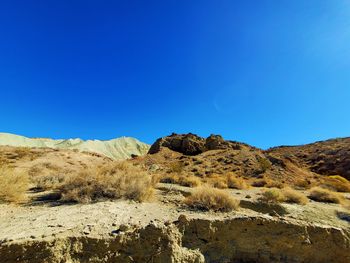 Scenic view of arid landscape against clear blue sky