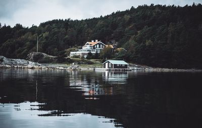 Scenic view of lake by buildings against mountain