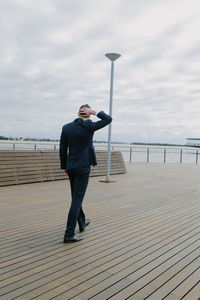 Full length of man standing on railing against sea