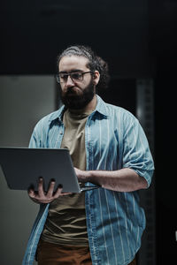 It technician working on laptop standing in server room