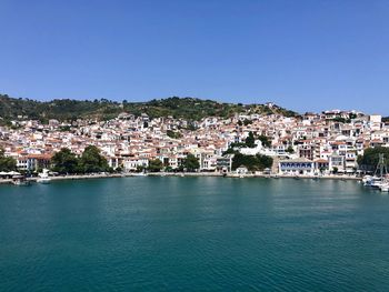 Townscape by sea against clear blue sky