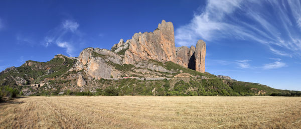 Scenic view of rock formation on field against sky