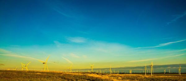 Wind turbines on field against blue sky