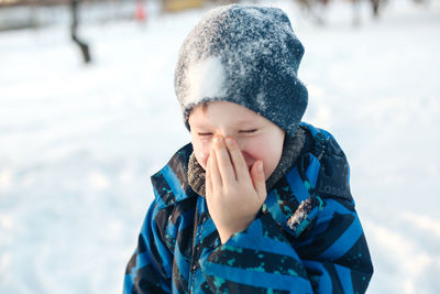 Close-up of smiling boy in snow outdoors