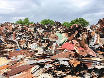 Heap of scrap metals against cloudy sky at garbage dump