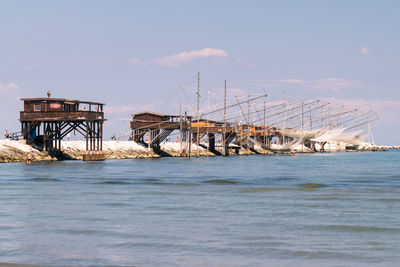 Cranes on pier over sea against sky