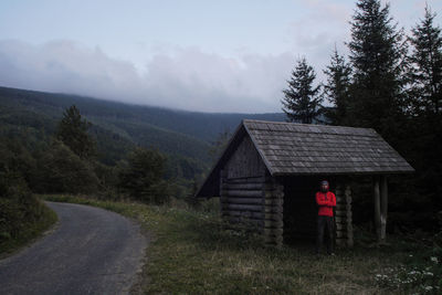 Man standing by log cabin against mountains