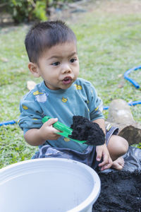 Portrait of cute baby boy sitting on field