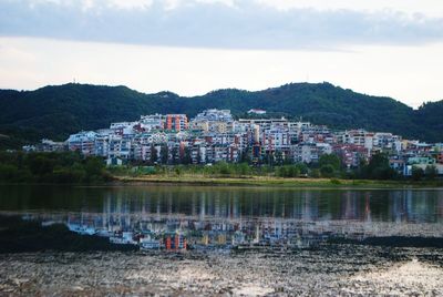 Houses by river against sky