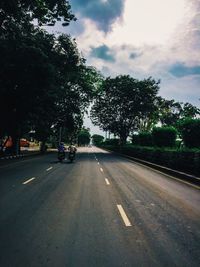 Road by trees against sky