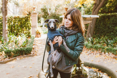 Smiling woman with dog standing outdoors