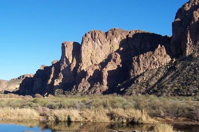 Rock formations on landscape against clear blue sky