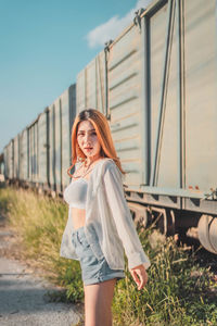 Portrait of young woman standing against sky