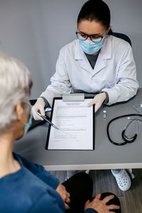 Doctor explaining to her patient consent form to coronavirus vaccine