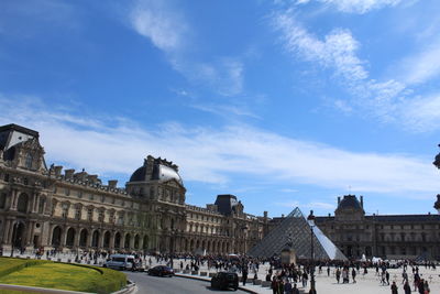 People in front of historical building against blue sky