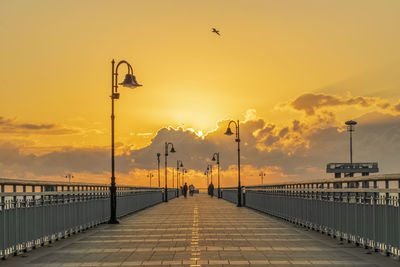 Street lights against orange sky during sunset