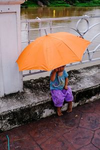Full length of girl standing on wet umbrella during monsoon