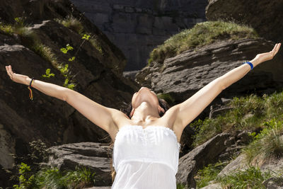 Woman raising her arms on the mountain in a white dress