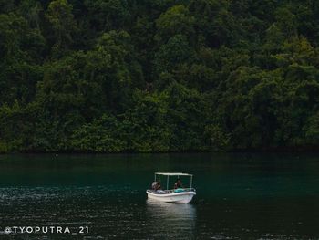 Boat sailing in lake by trees in forest