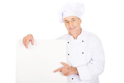 Mature chef holding blank placard against white background
